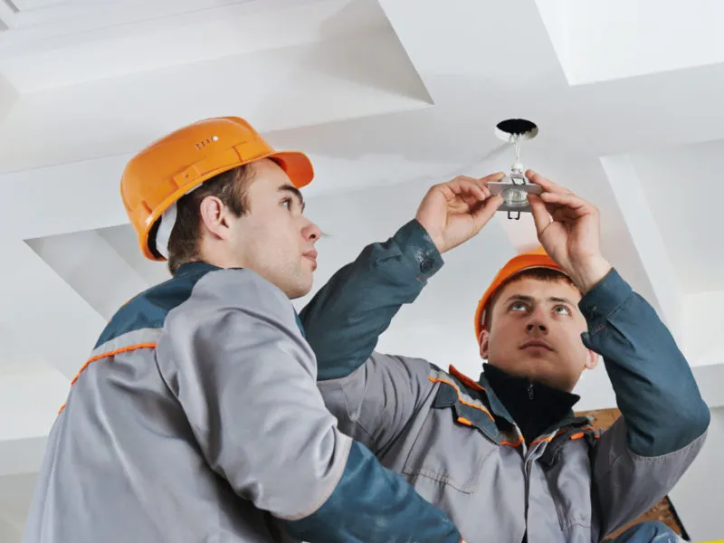 Electricians fitting light fixture